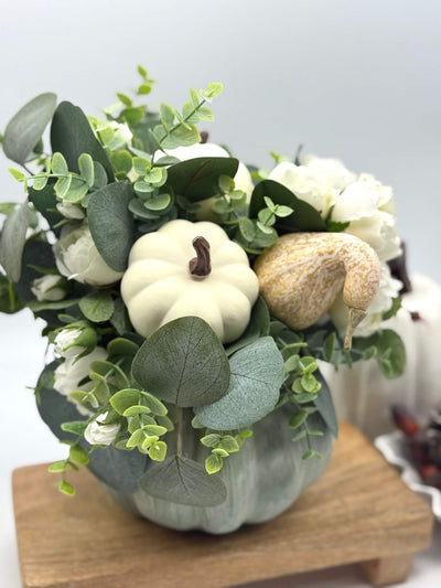 fall centerpiece with white roses, eucalyptus stem, ivory and beige pumpkins on wooden pumpkin in sage color