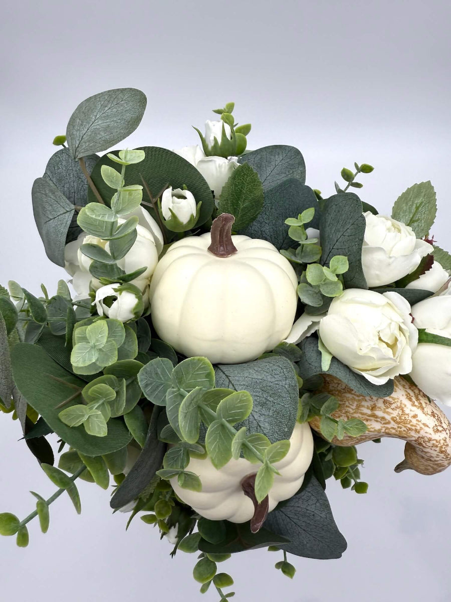 view from top fall centerpiece with white roses, eucalyptus stem, ivory and beige pumpkins on wooden pumpkin in sage color