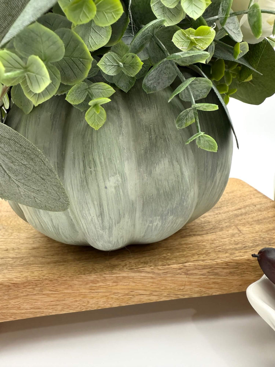 close up for fall centerpiece with white roses, eucalyptus stem, ivory and beige pumpkins on wooden pumpkin in sage color