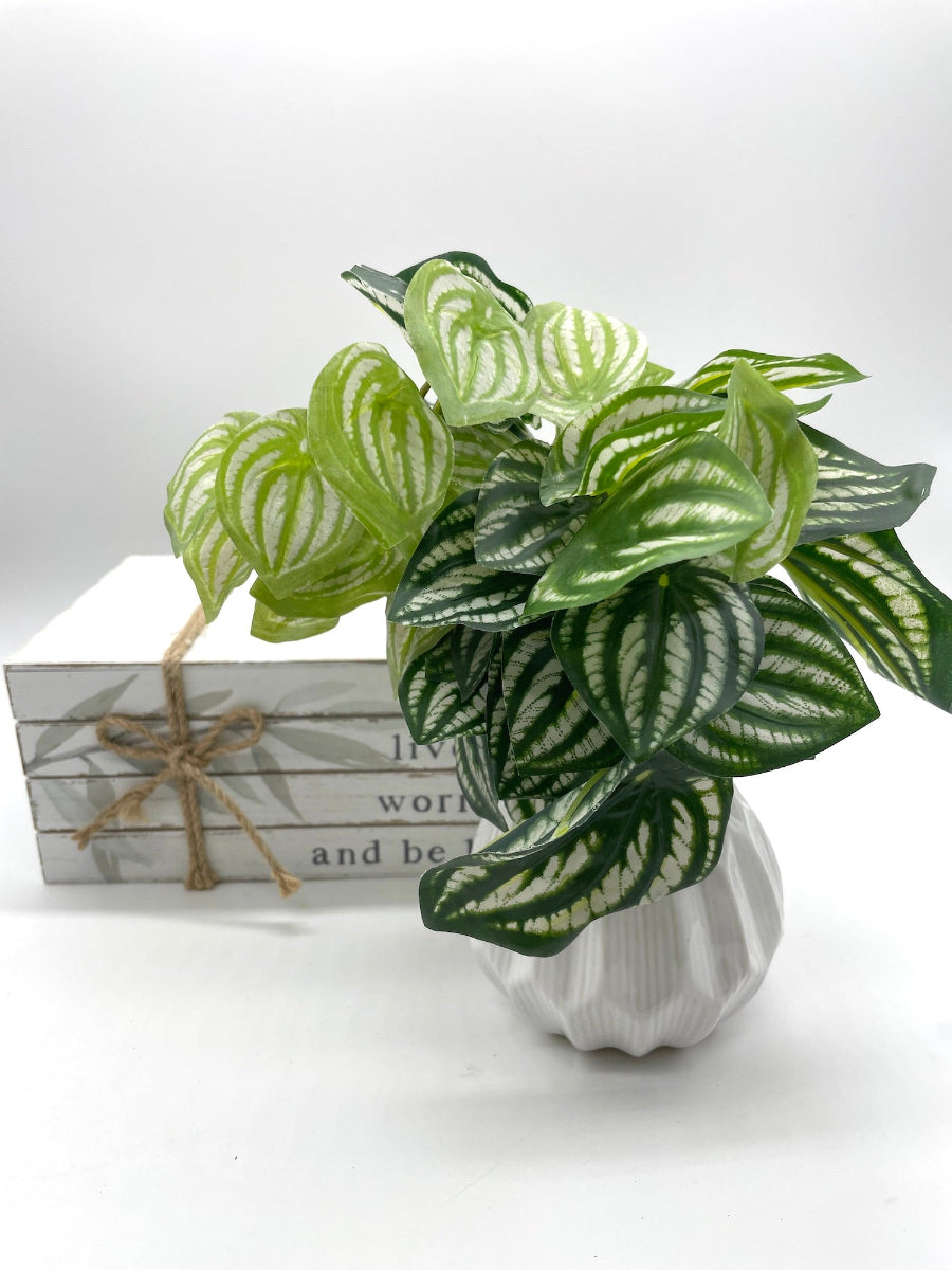 realistic looking faux plant with green leaves and white stripes in white ceramic geometric vase