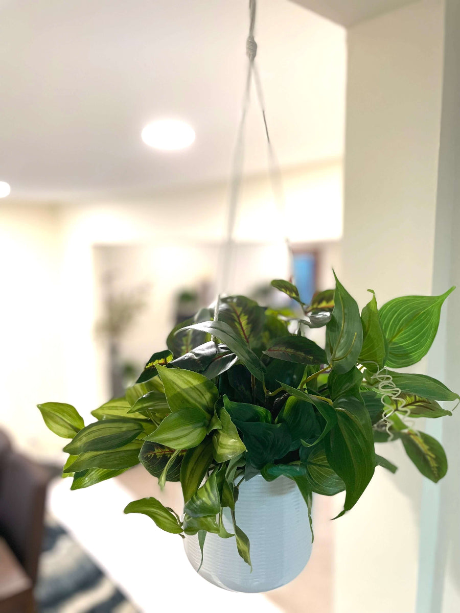 mix of faux plants of variety of green shades and shape in white ceramic hanging pot