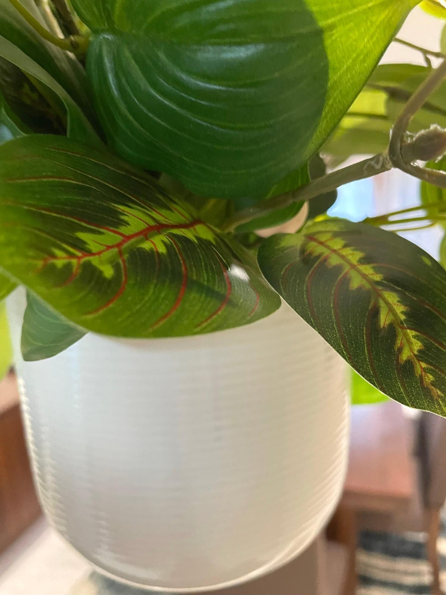 mix of faux plants of variety of green shades and shape in white ceramic hanging pot