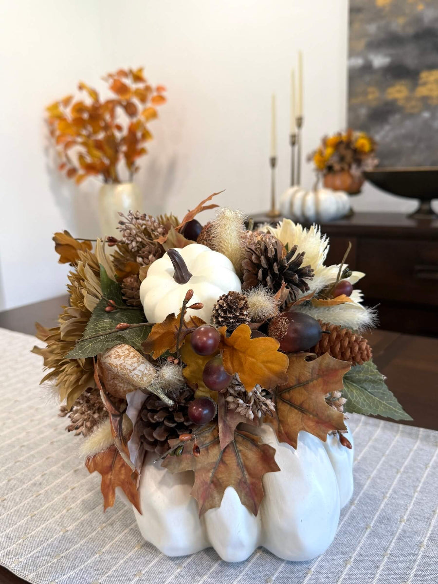 large fall arrangement with flowers, pumpkin, leaves, autumn berries on large white wooden pumpkin