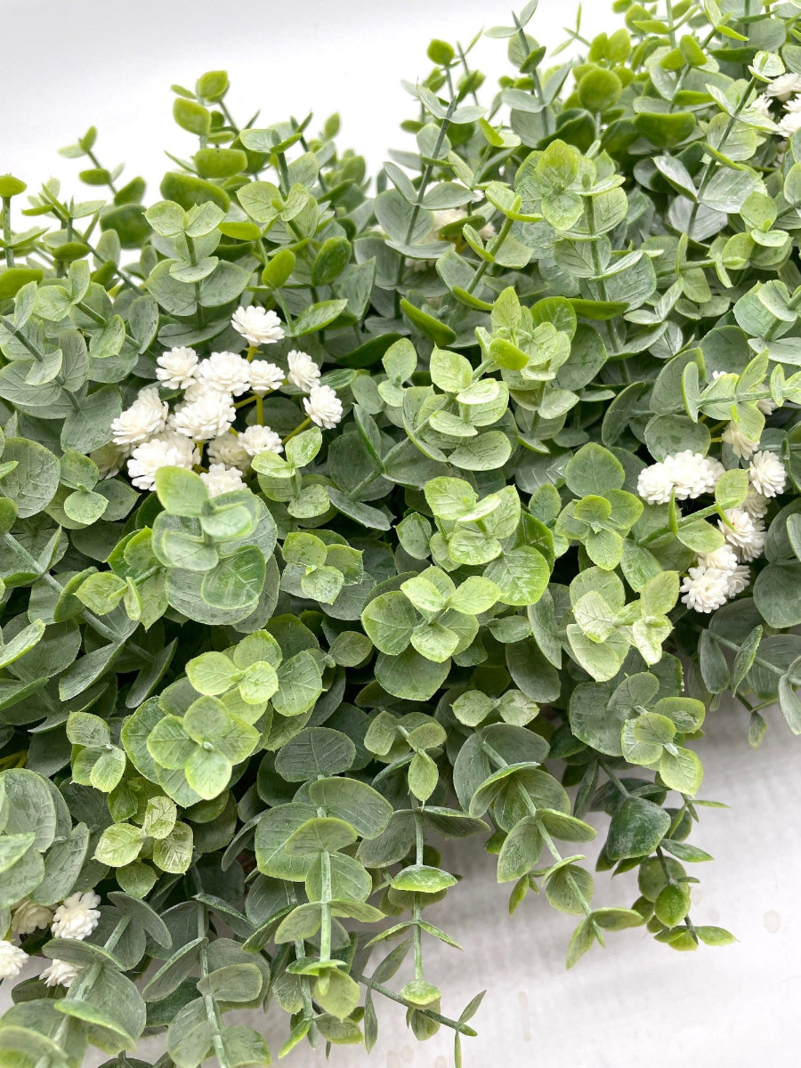 close up for faux eucalyptus arrangement with delicate white flowers in wooden planter