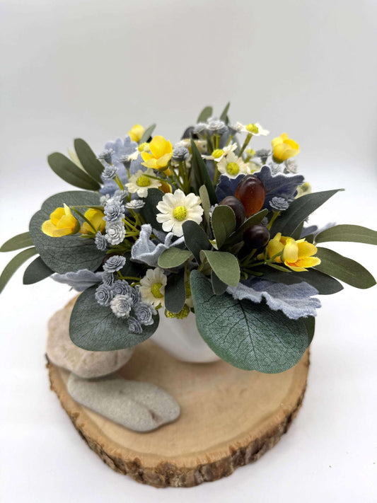 small artificial floral arrangement in whote ceramic vase