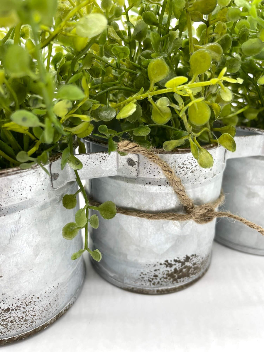 close up for vivid green faux greenery in triple can metal galvanized planter with handles decorated with jute, in modern farmhouse style