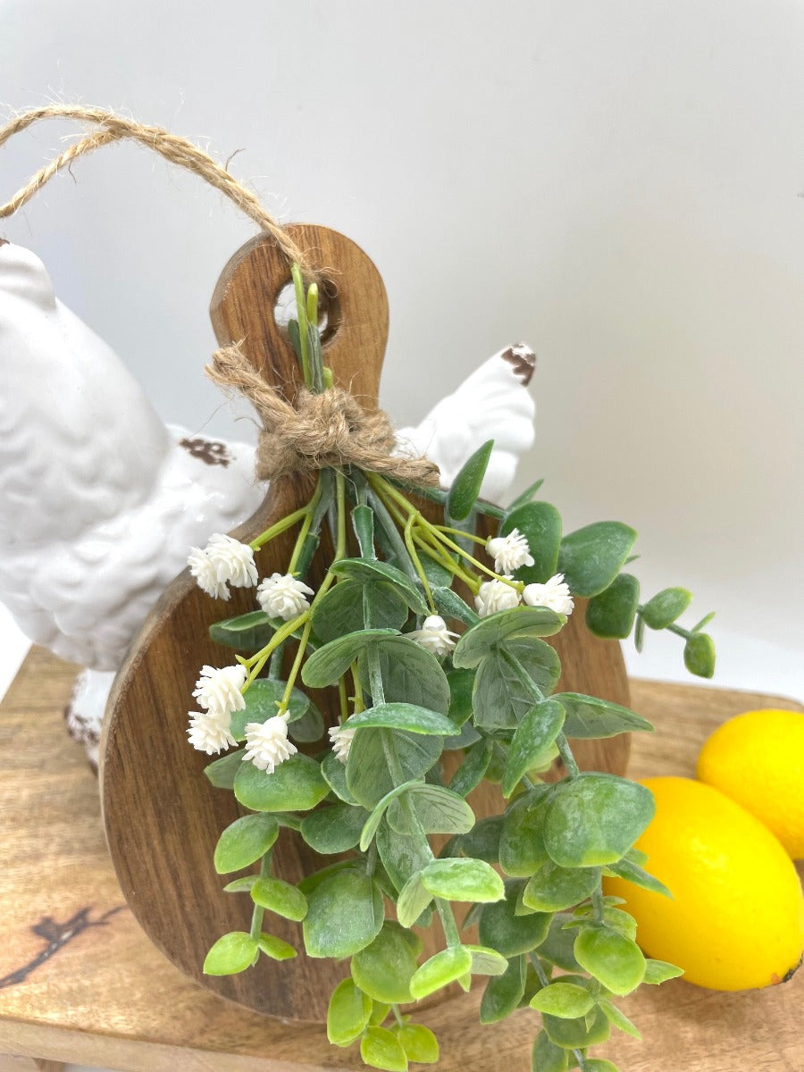 close up for Mini Cutting round wooden Board Decorated with eucalyptus stems and white flowers and finished with jute