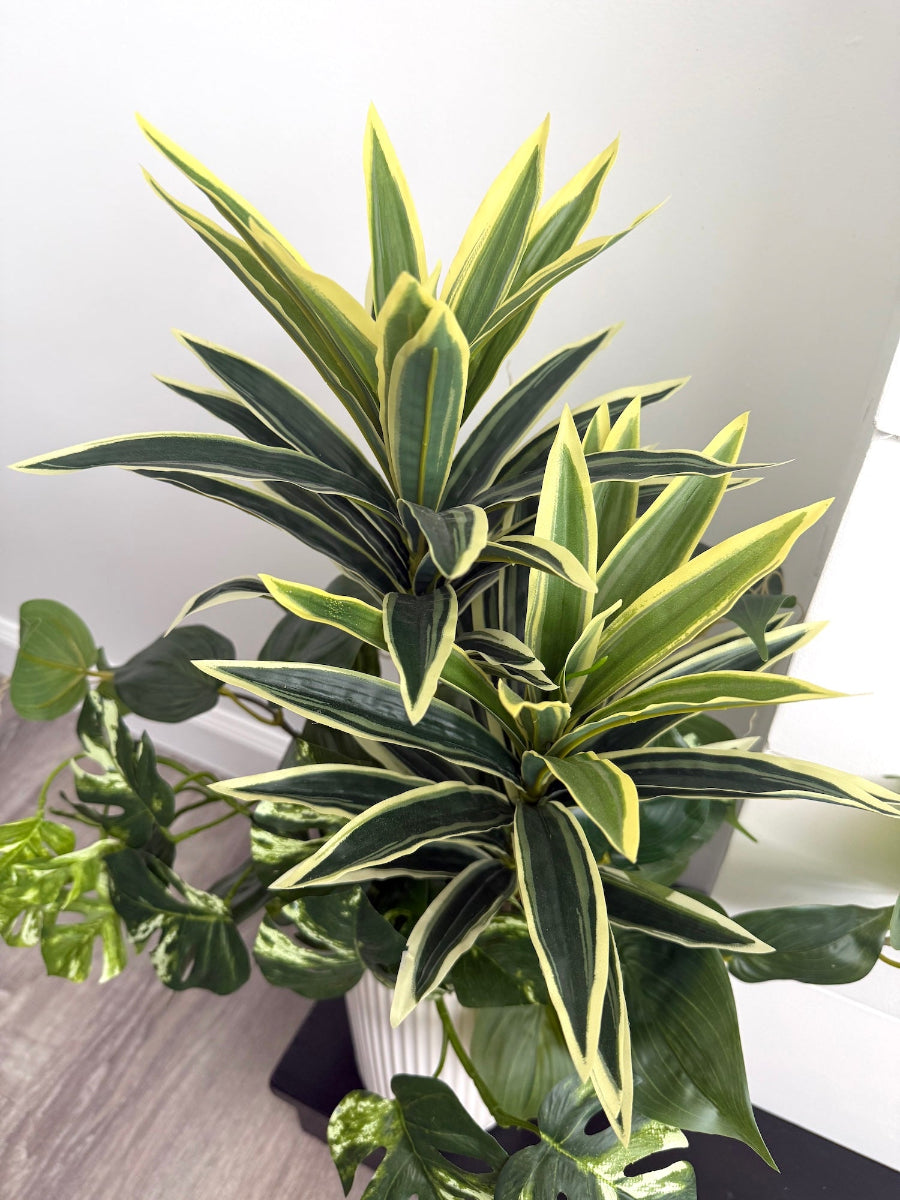 view from top of tall arrangement, mix of 3 realistic looking vivid green faux plants with leaves in green and green-white, placed in tall white ceramic textured pot vase