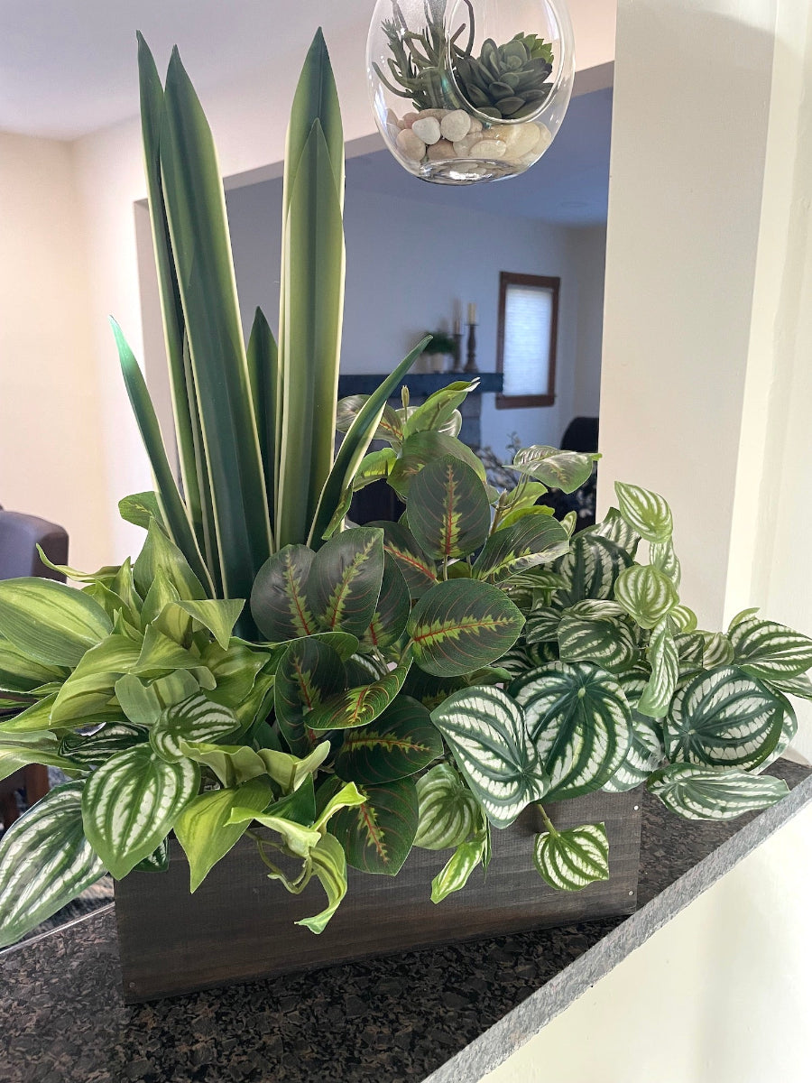 mix of tall and lush faux plants of variety of green colors and white accents in wooden planter stained is expresso color