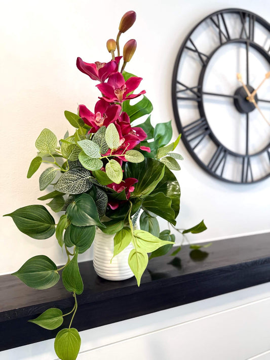 elegant vivid pink orchid and variety of greenery in ceramic white vase