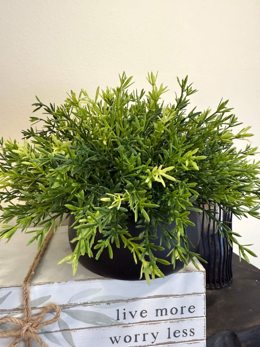 lifelike faux plant in few shades of green potted in low cearmic black pot vase