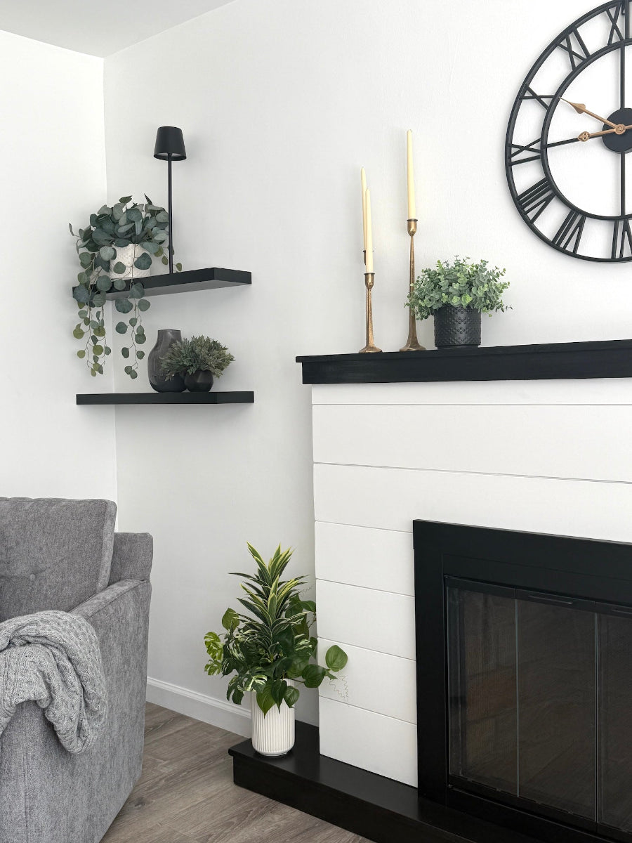 virew from living room of tall arrangement, mix of 3 realistic looking vivid green faux plants with leaves in green and green-white, placed in tall white ceramic textured pot vase