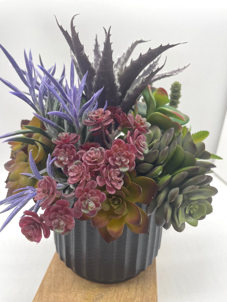 Faux Succulent Centerpiece-mix f variety of succulents in different shapes and style  in variety of green to burgundy and purple, all set in textured black ceramic pot vase