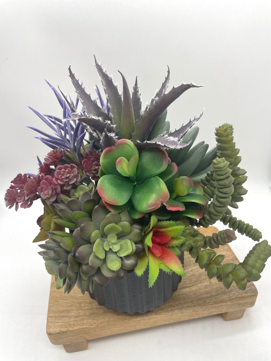 view from top of Faux Succulent Centerpiece-mix f variety of succulents in different shapes and style  in variety of green to burgundy and purple, all set in textured black ceramic pot vase