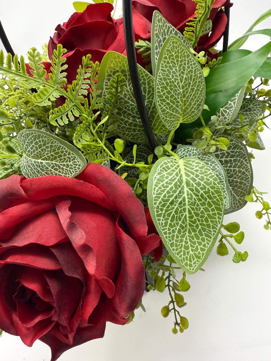 Close-up of red roses and green leaves of arrangement in black gift bag
