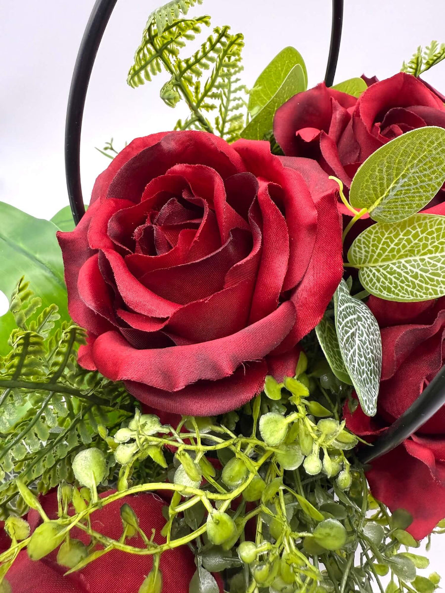 close-up of Bouquet of realistic red roses with greenery in a black gift bag