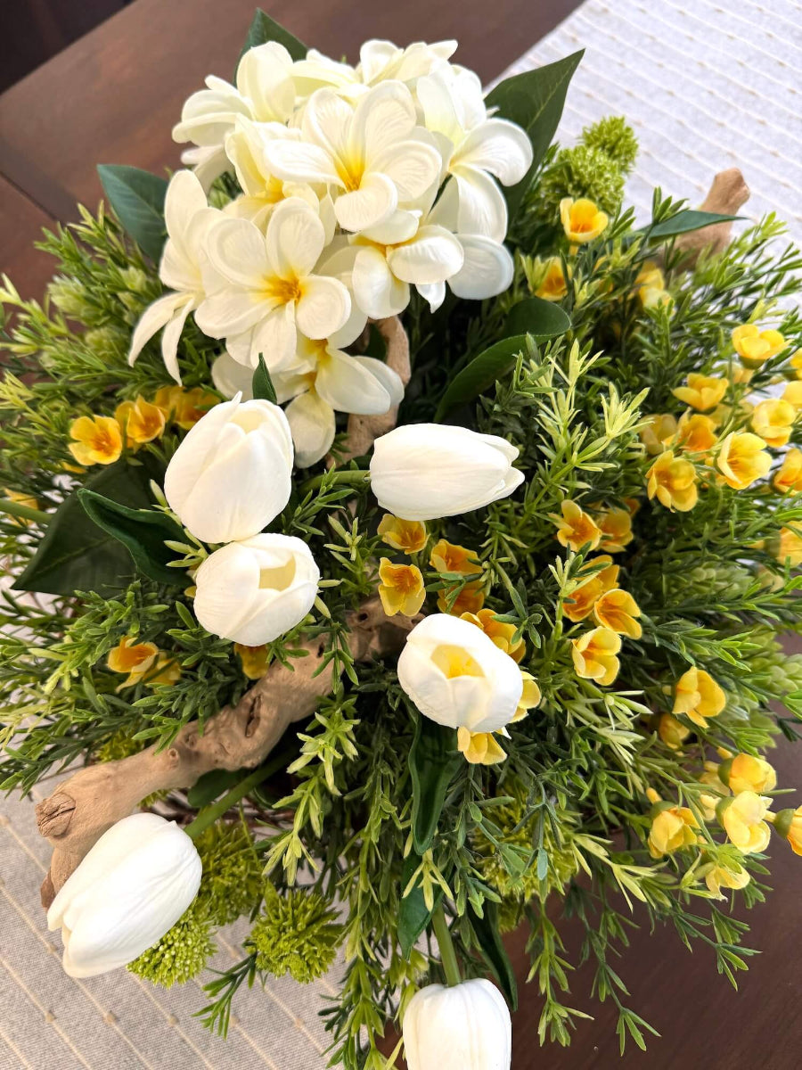 view from top on spring centerpiece with white tulips, white primrose, yellow flowers, driftwood, vivid greenery
