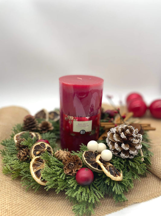 Christmas wreath table arrangement decorated with pinecones, dried lemon slices, cinnamon sticks, cranberry and red pillar candle