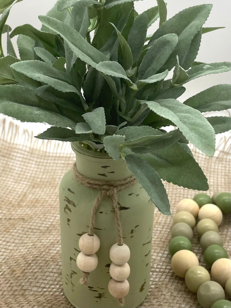 realistic looking faux sage plant in bottle vase painted in sage and distressed and decorated with juste with wooden beads