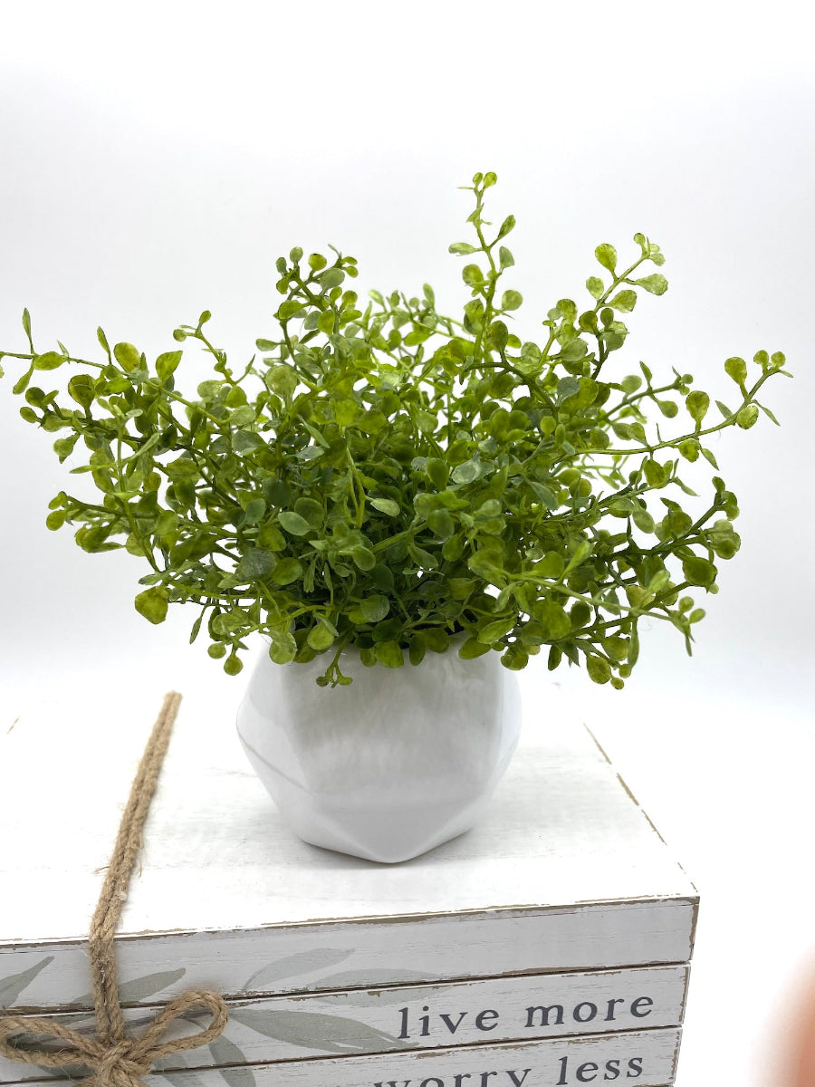 realistic faux greenery in white ceramic vase in geometric shape
