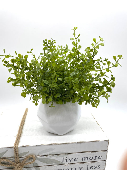 realistic faux greenery in white ceramic vase in geometric shape