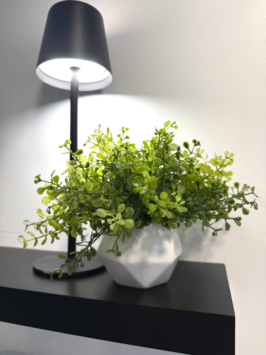 faux plant vivid green stems in white ceramic pot vase of geometric shape styled on shelf