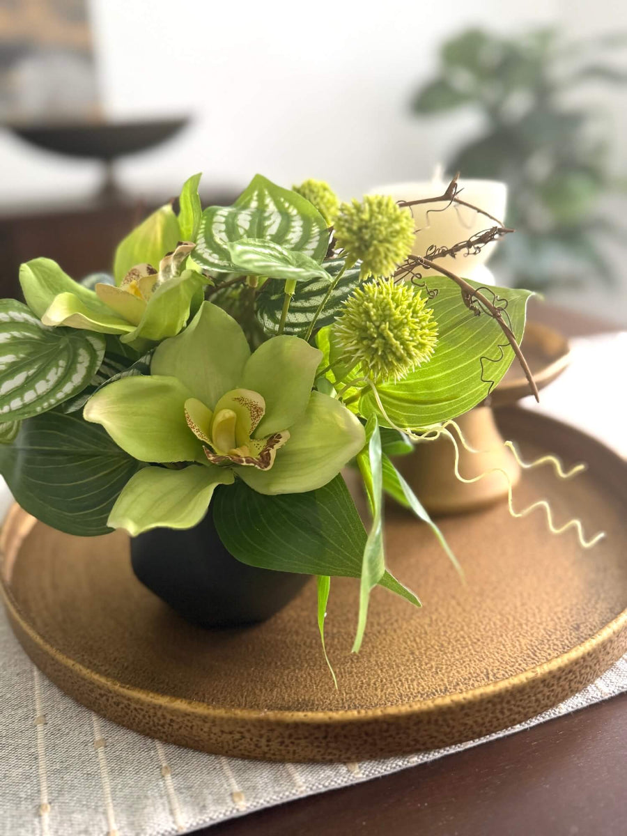 realistic looking green orchid small arrangement with greenery in black ceramic vase