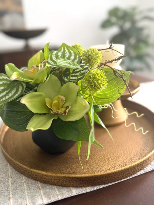 realistic looking green orchid small arrangement with greenery in black ceramic vase