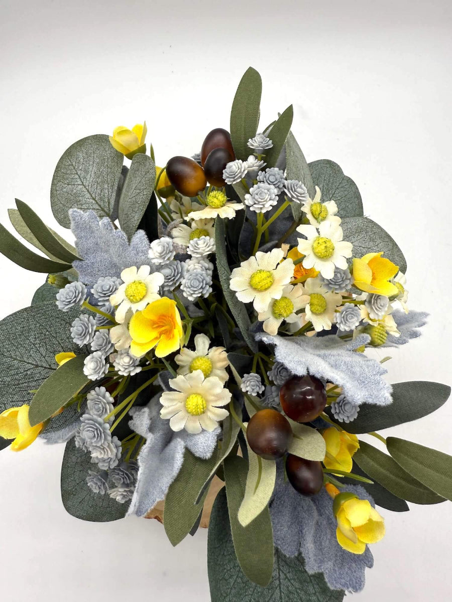view from top of small artificial floral arrangement in white ceramic vase with variety of floral and olive stems