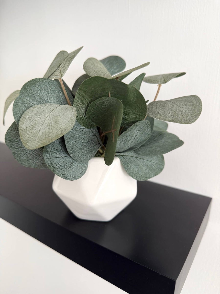 realistic looking small silver dollar eucalyptus arrangement in white ceramic vase for shelf