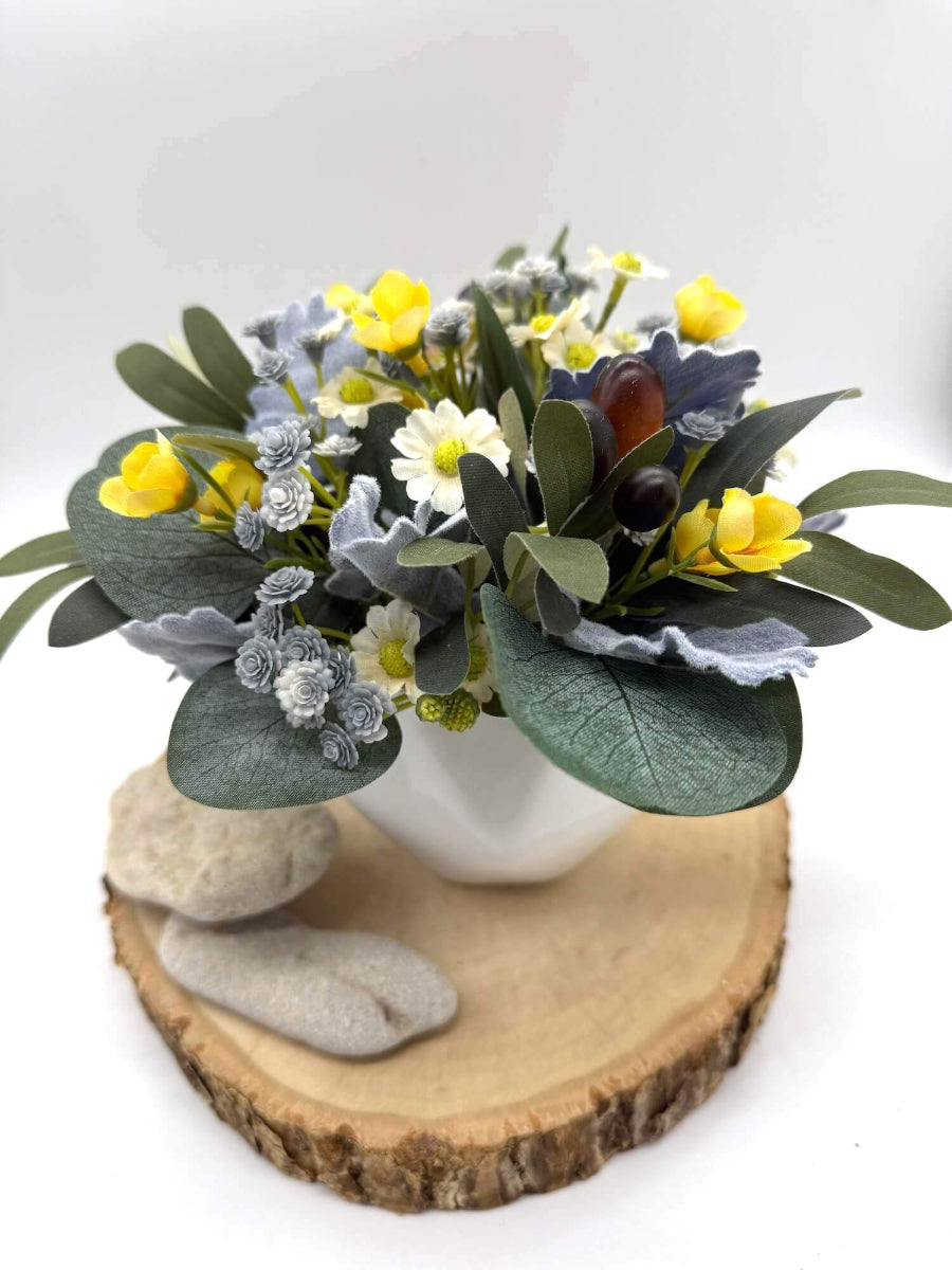 small artificial floral arrangement in white ceramic vase