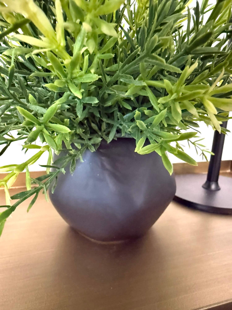 small vivid green realistic faux plant in black matte ceramic pot vase of geometric shape
