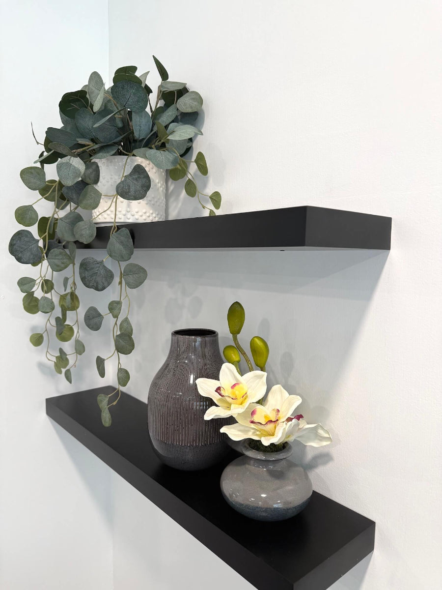 small white orchid arrangement in gray ceramic vase shelf decor