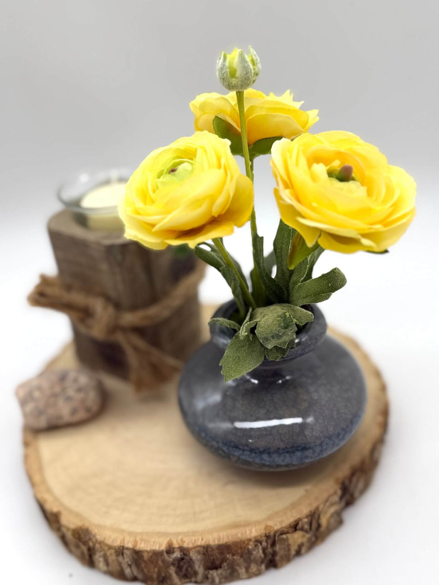small yellow runcunculas bouquet in gray ceramic vase