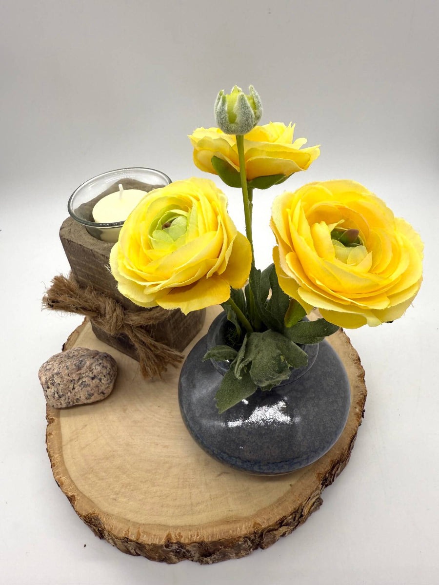 small yellow runcunculas bouquet in gray ceramic vase