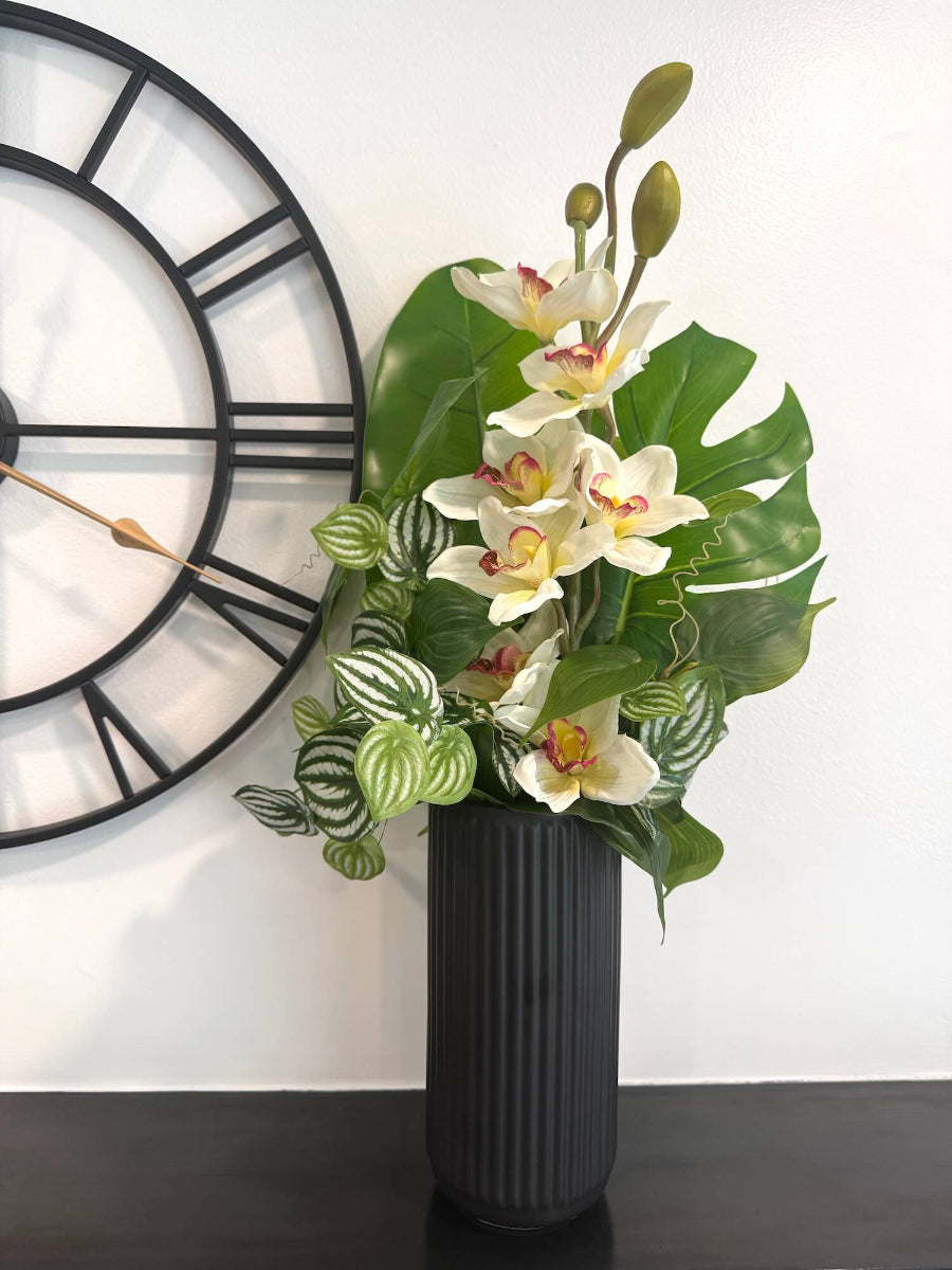 realistic looking tall faux white orchid arrangement accompanied with greenery in black matte textured ceramic vase