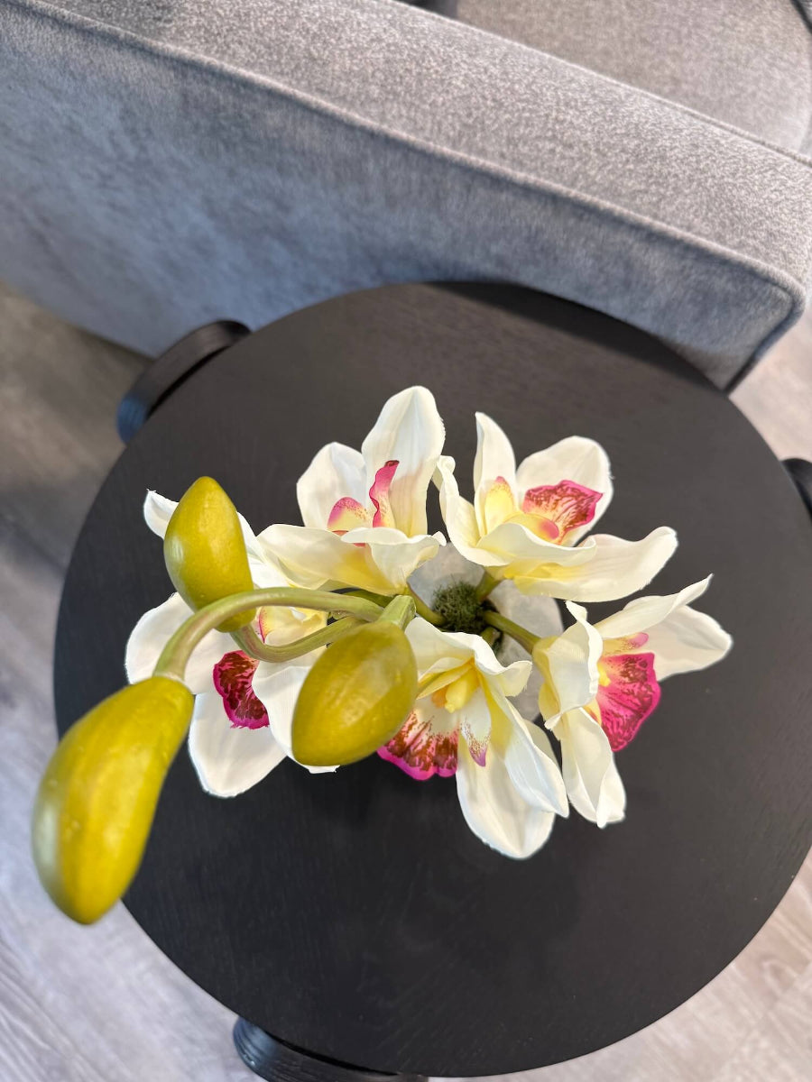 view from top of realistic looking small white orchid arrangement of five flowers and 3 buds in gray ceramic vase styled on coffee table