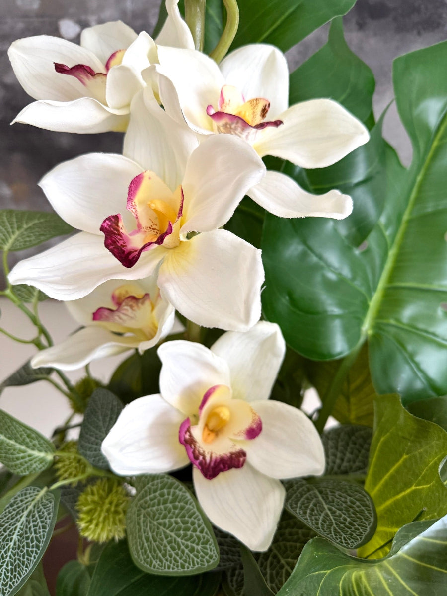 artificial white orchid and greenery in tall gold vase