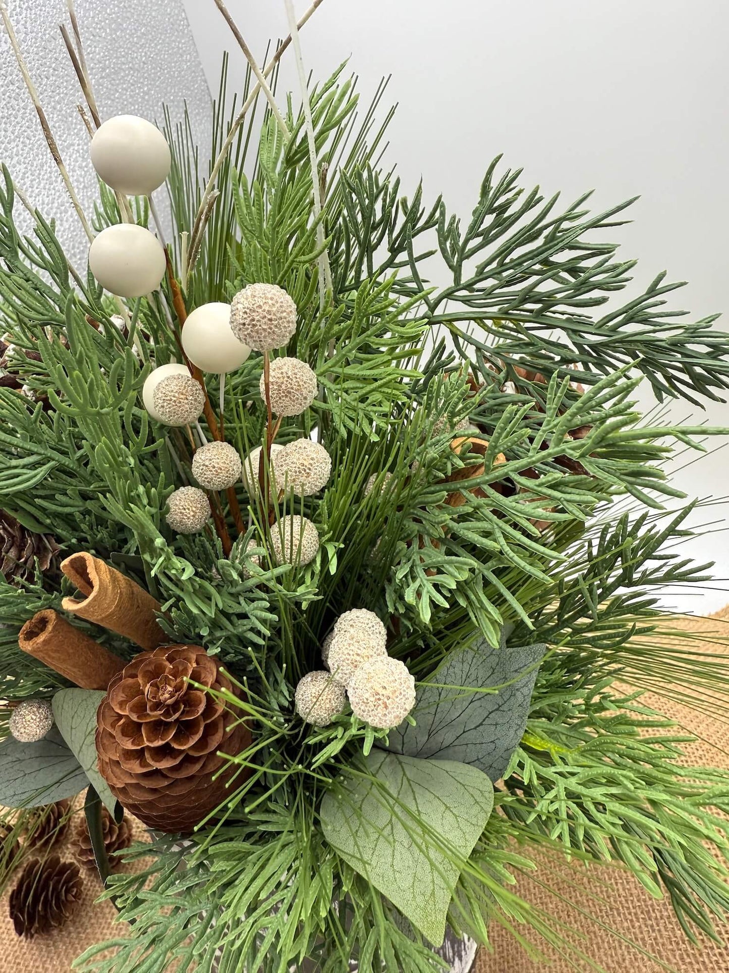 close up for winter arrangement of greenery, pinecones, cinnamon sticks 