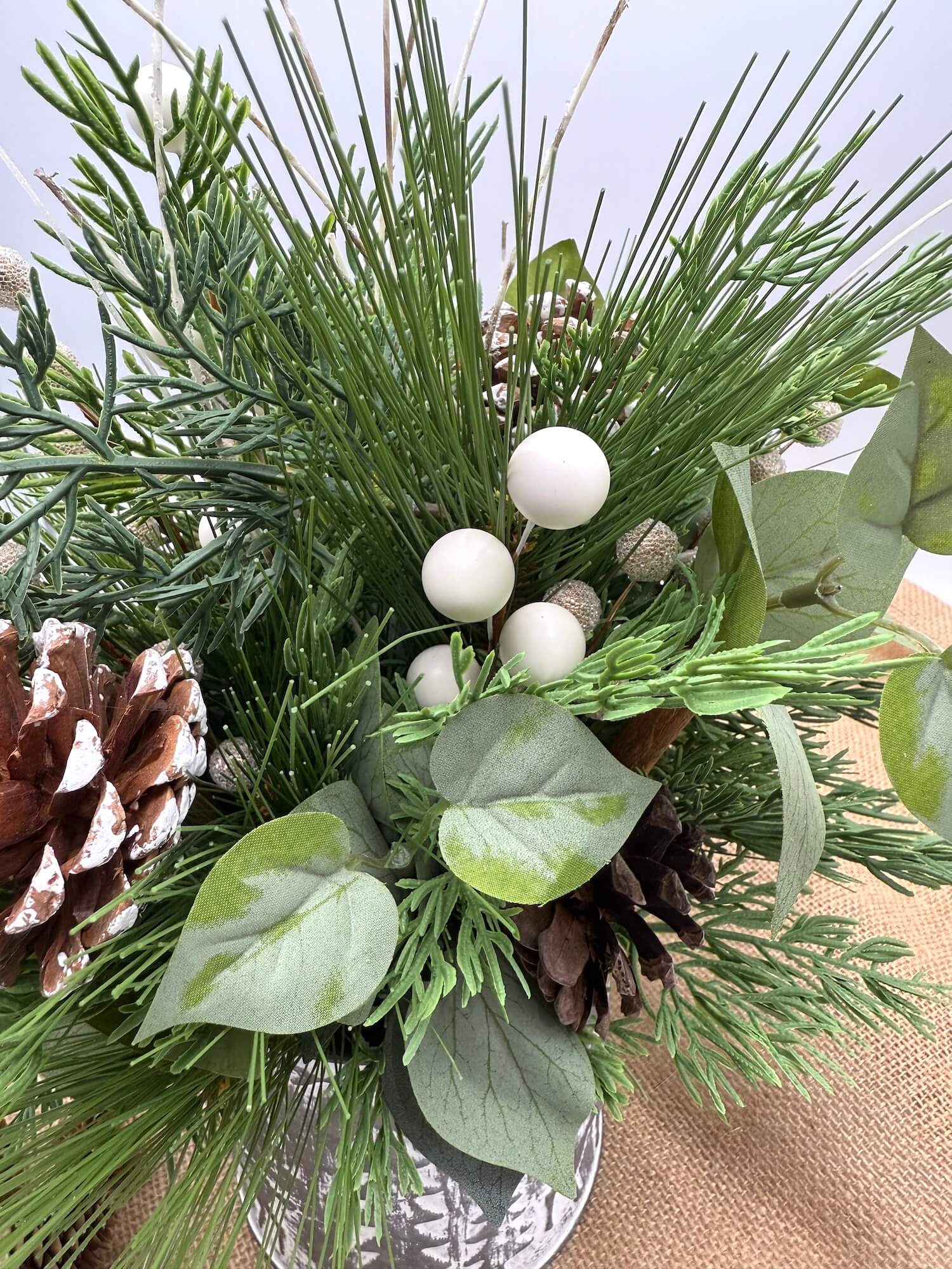 closeup of winter greenery arrangement with natural elements of pinecones