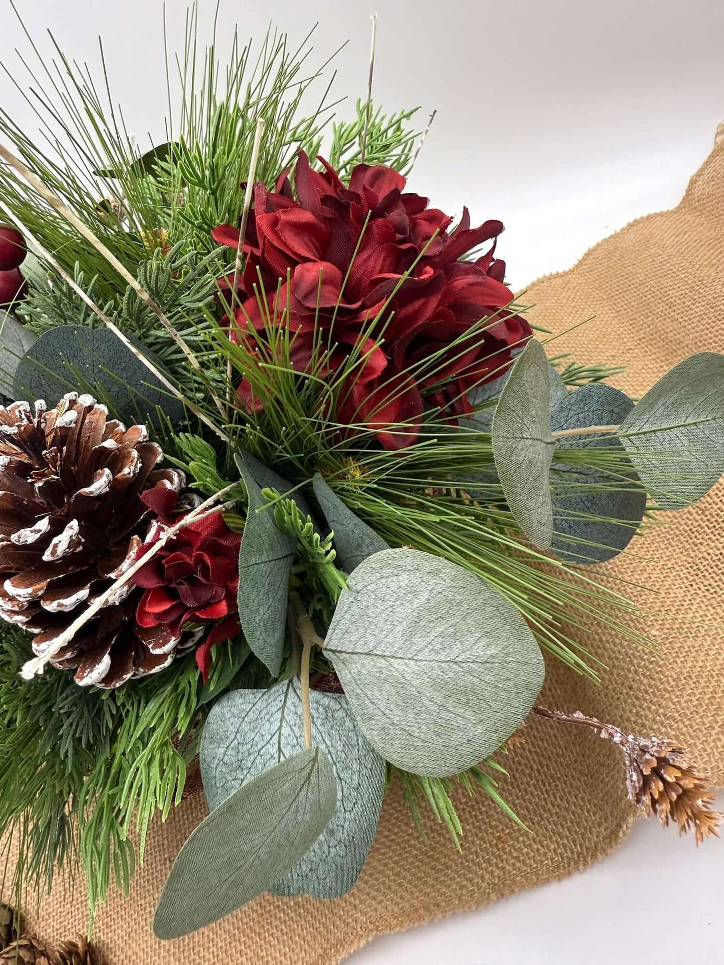 burgundy flowers in winter arrangement with pinecones and christmas accents