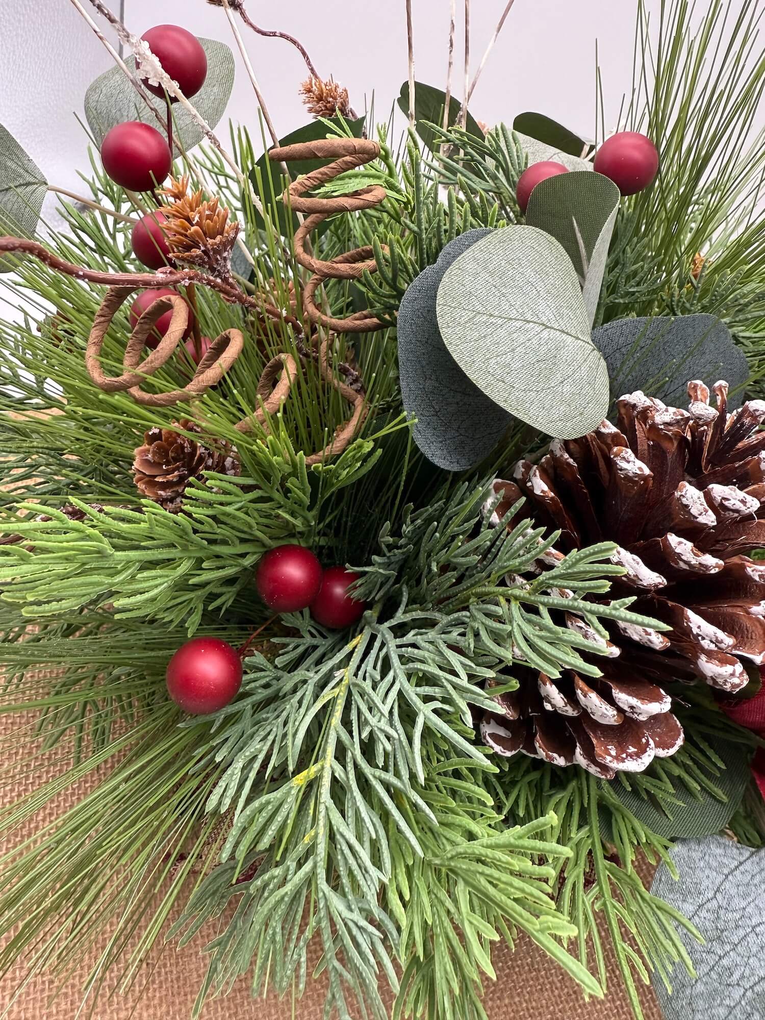 Christmas arrangement with winter greenery, pinecones, and red berries 