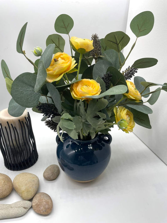 realistic faux bouquet of yellow runcunculas flowers silver eucalyptus stem and black wheat stems in navy blue ceramic vase