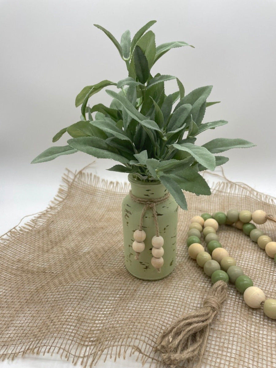 realistic looking faux sage arrangement in bottle vase painted in green sage and distressed, decorated with jute and wooden beads