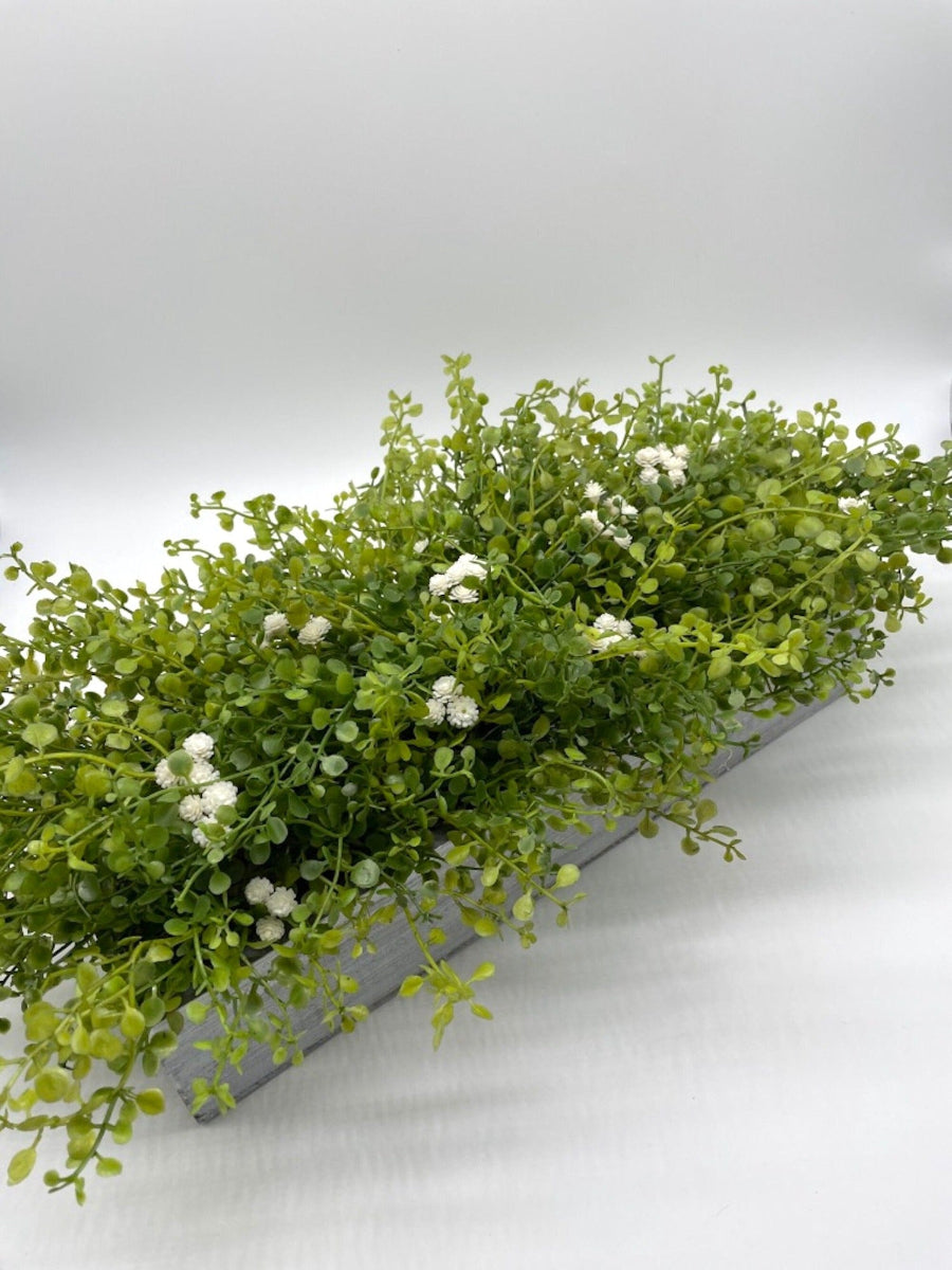 view from top of realistic looking vivid green faux Greenery Arrangement with delicate white flowers  in long Whitewashed Wooden Planter