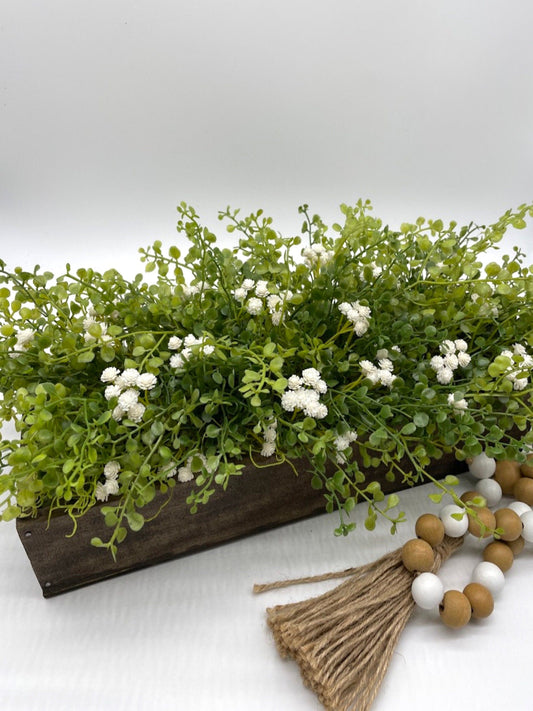 vivid green realistic looking faux greenery with white flowers in long wooden planter stained is expresso color