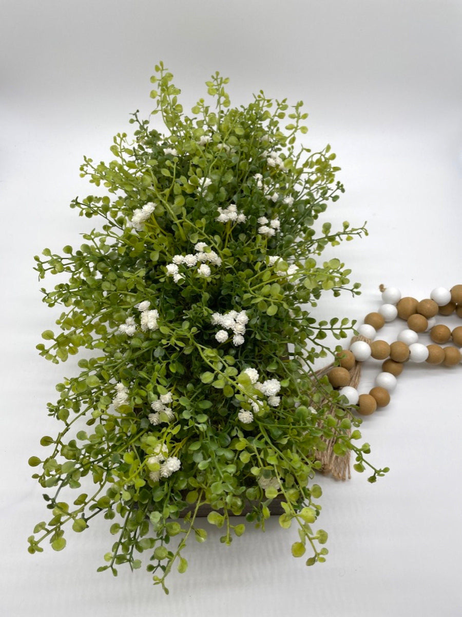 view from top for vivid green realistic looking faux greenery with white flowers in long wooden planter stained is expresso color
