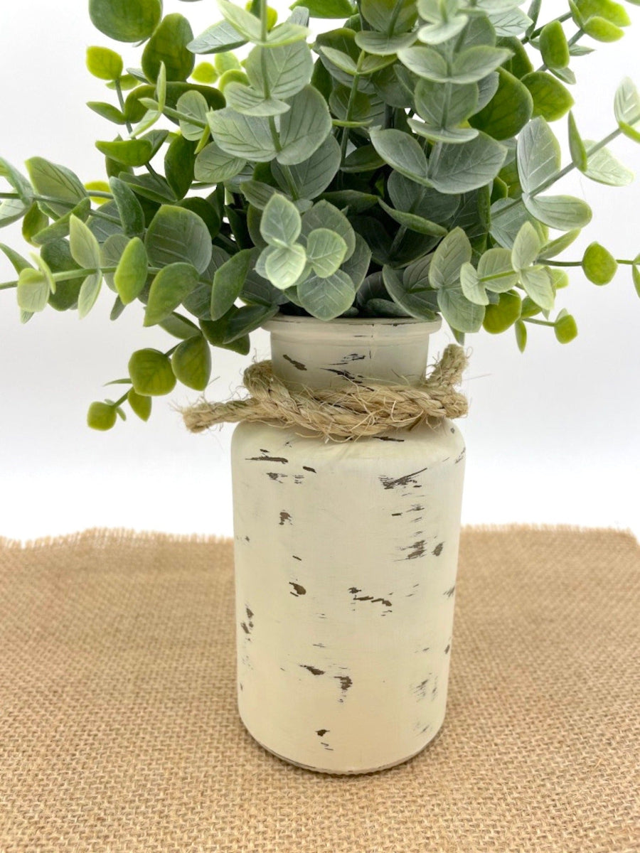 close up for realistic faux Eucalyptus Arrangement in bottle vase painted in ivory and distressed and decorated with rope