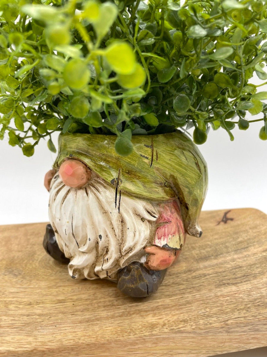 close iup side view of vivid green realistic faux plants in gnome shaped ceramic pot vase