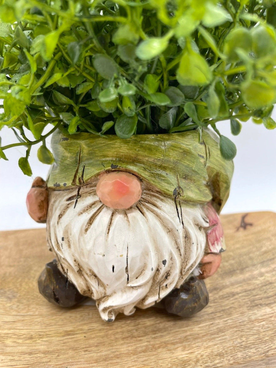 close up for vivid green realistic faux plants in gnome shaped ceramic pot vase